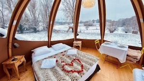 Un cuarto acogedor y circular con una cama, una mesita y una lámpara colgante.