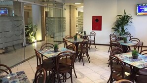 A restaurant with glass walls, wooden tables, and chairs. - Portal da Princesa Hotel (Feira de Santana)