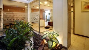 A modern interior with a glass partition, indoor plants, and a wooden floor. - Portal da Princesa Hotel (Feira de Santana)