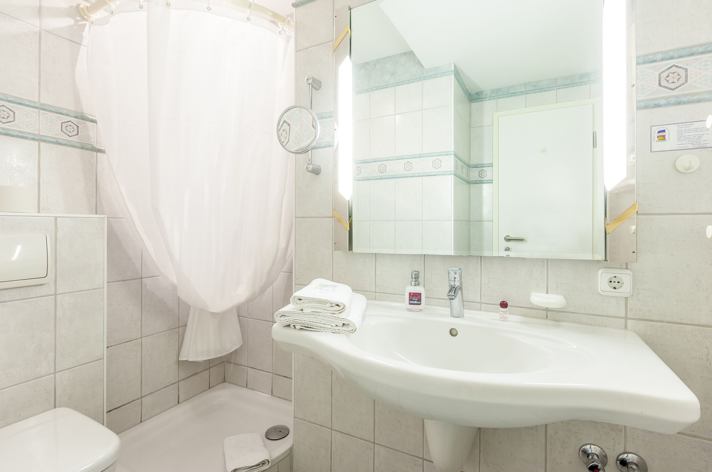 A bathroom with a white sink, a mirror, and a shower curtain.