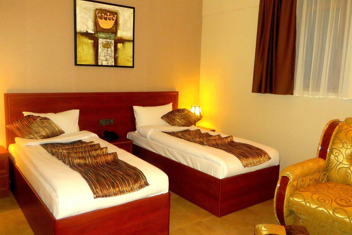 Ein Hotelzimmer mit zwei Betten, einem Sessel und einem Bild an der Wand.