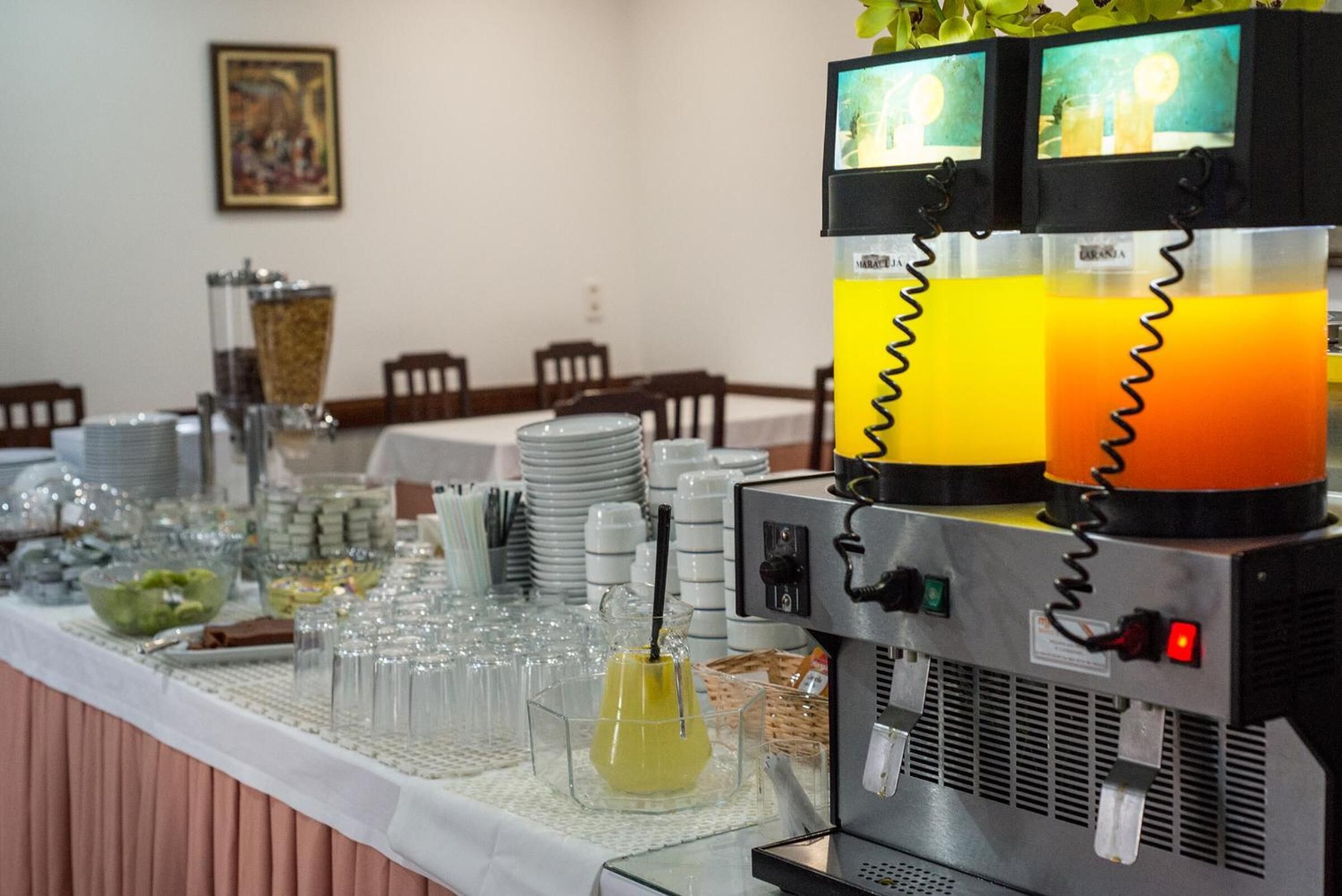 Un buffet avec un distributeur de jus, de la verrerie et différents récipients pour les aliments.