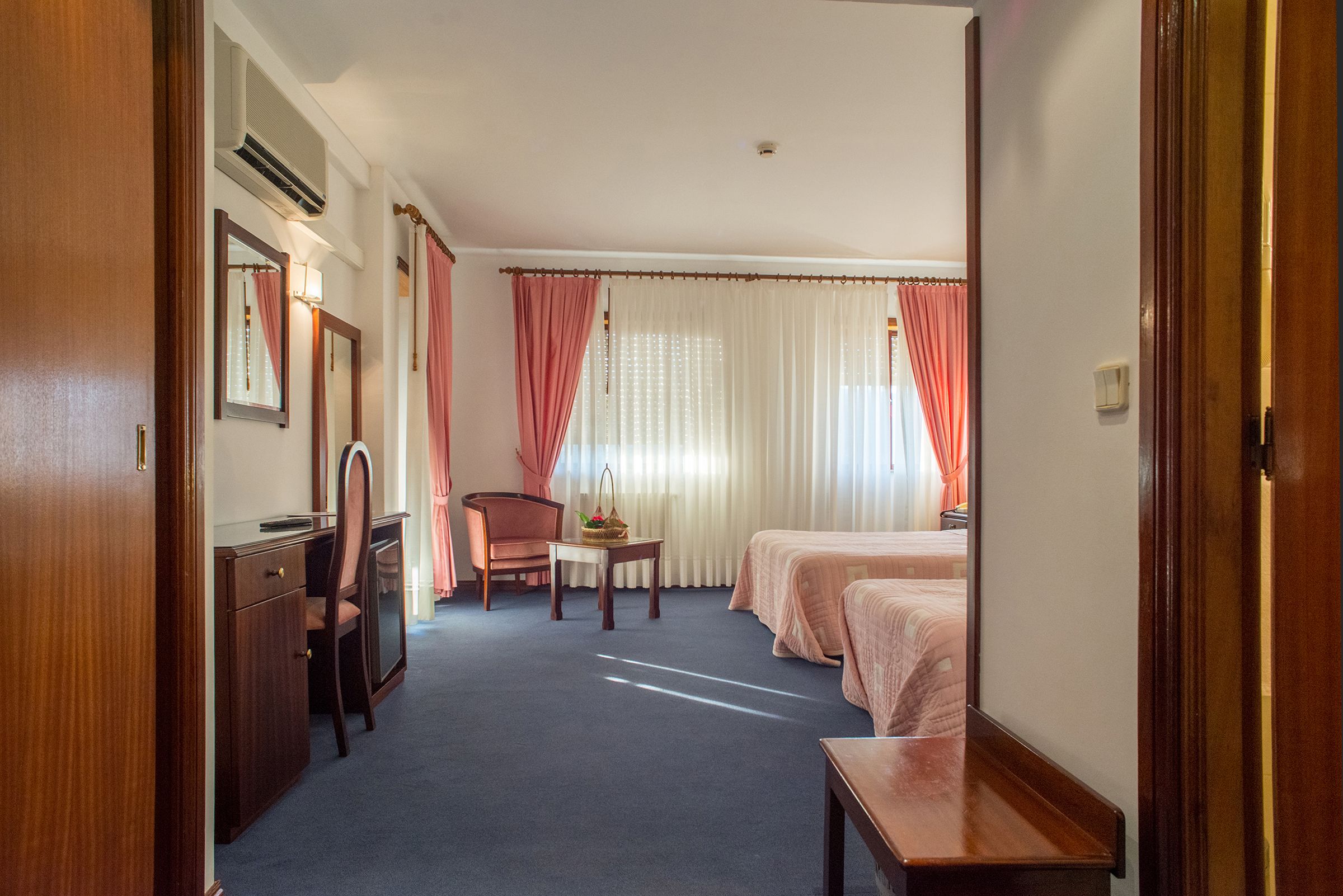 Una habitación de hotel con escritorio, silla, dos camas y una mesita.