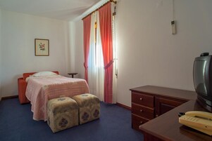 Un dormitorio con cama, cómoda de madera, televisor y teléfono.