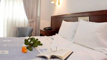 A neatly made bed with white linens, a bedside lamp, and a book on the bed.