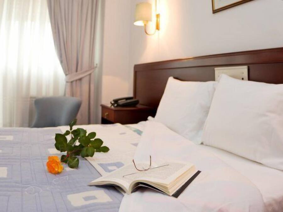 A neatly made bed with white linens, a bedside lamp, and a book on the bed.