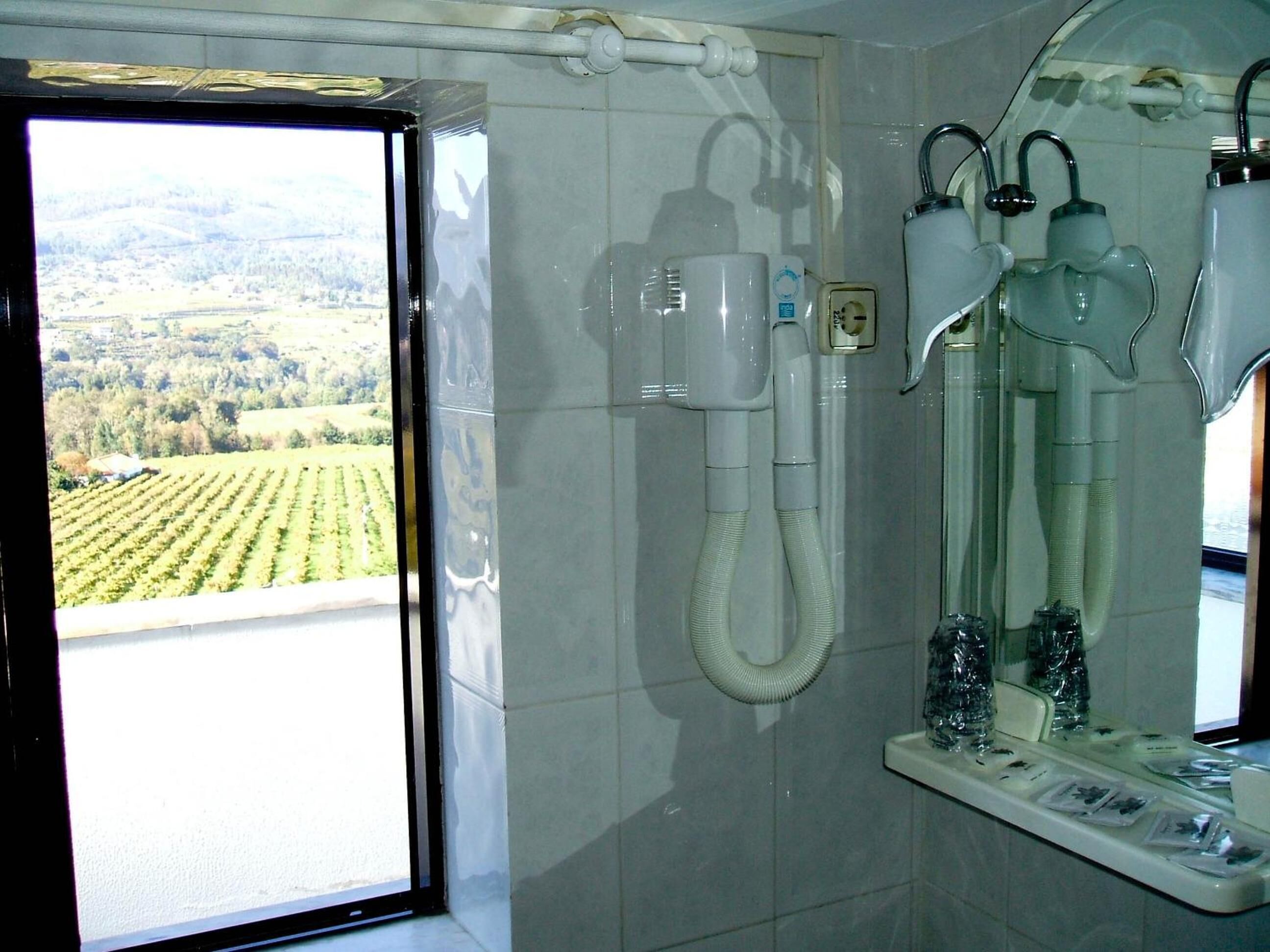 A bathroom with a large window, a shower, and a mirror.