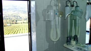 A bathroom with a large window, a shower, and a mirror.