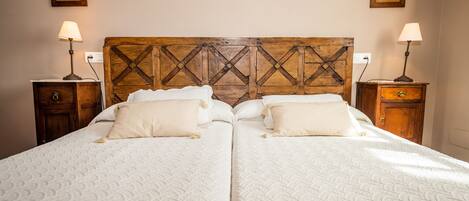 A double bed with a wooden headboard, two bedside tables with lamps, and two wall-mounted picture frames.