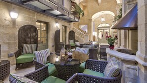 An indoor courtyard with wicker furniture, a glass table, and a stone wall.