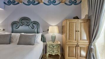 A bedroom with a bed, a nightstand, a lamp, a wooden cabinet, and a curtain.