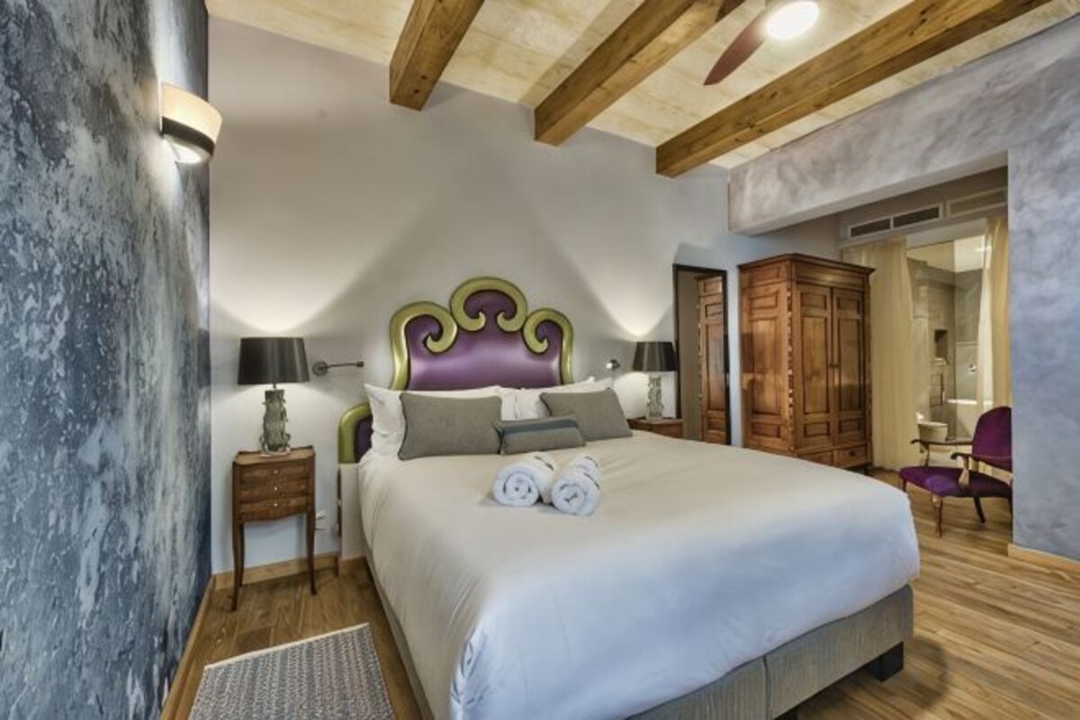 Un dormitorio con una cama grande, cabecera de madera, mesitas de noche y un armario.