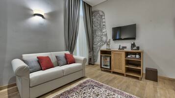 A living room with a sofa, a coffee table, a TV, a cabinet, and a patterned rug.
