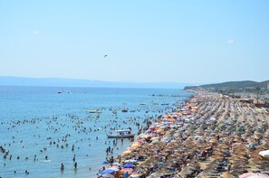 Una playa llena de gente nadando y tomando el sol bajo sombrillas.