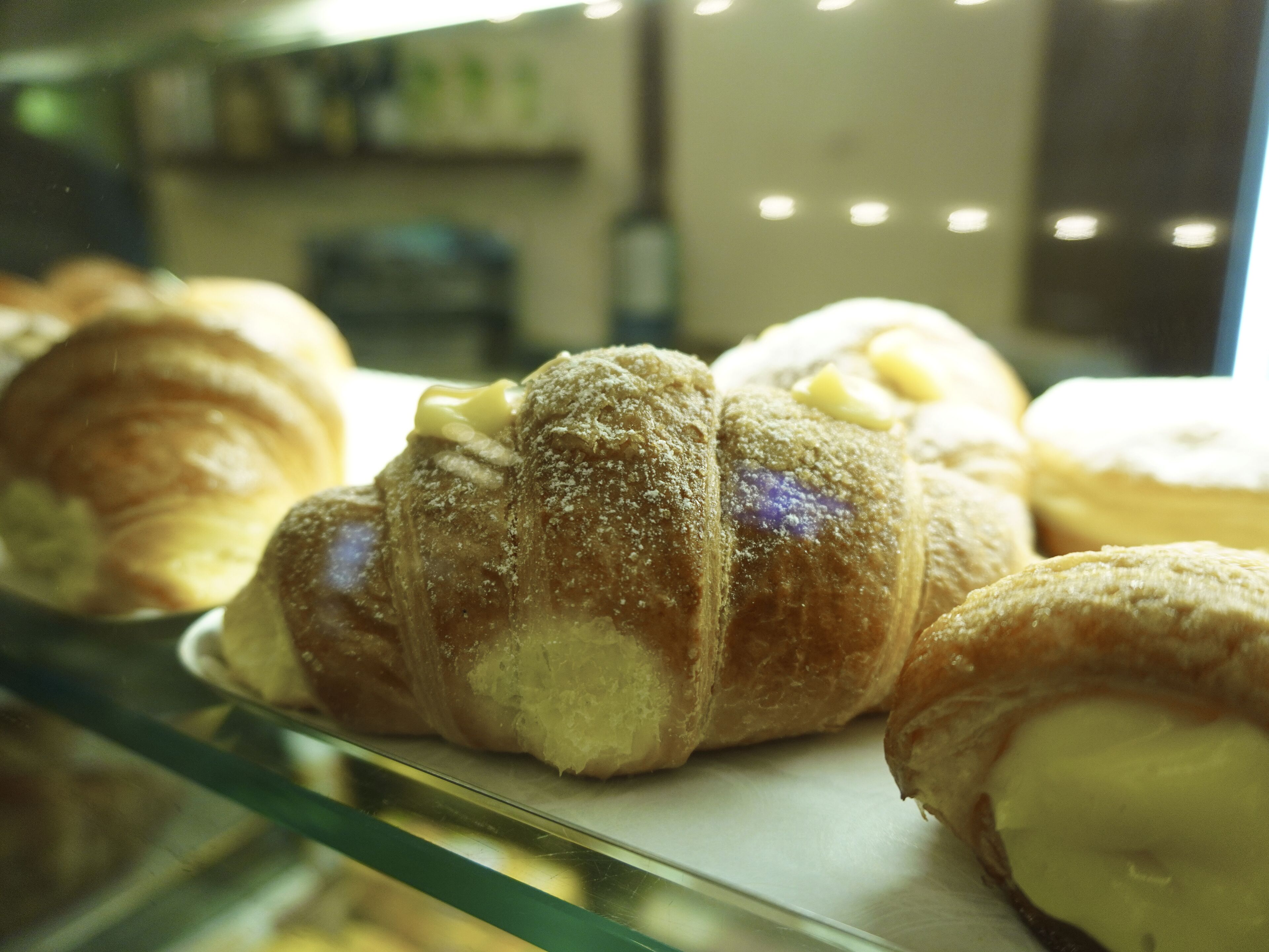 Una vitrina con diversos pasteles, incluyendo croissants y otras delicias horneadas.