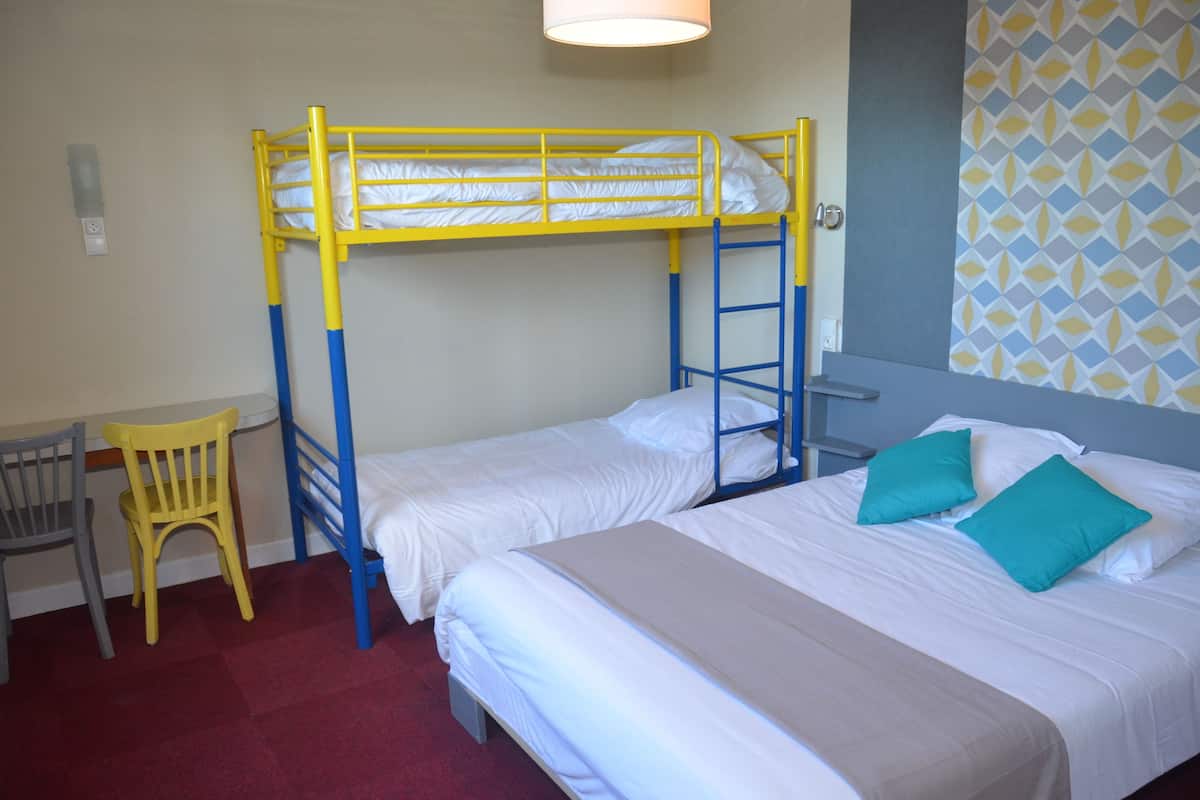 A room with two bunk beds, a desk, and a chair.