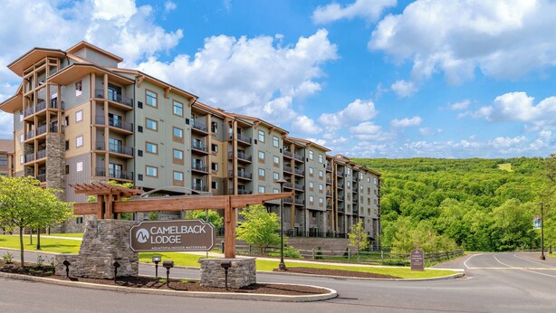 Ein mehrstöckiges Hotel mit Steinverkleidung, Balkonen und einem Schild, das Camelback Lodge Aquatopia Indoor Waterpark anzeigt.