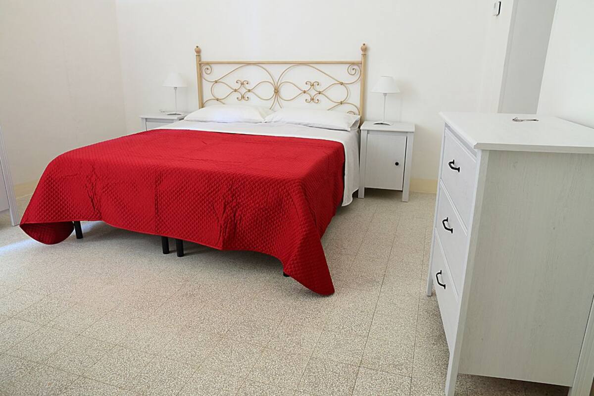 Un dormitorio con cama, mesitas de noche, cómoda y espejo.