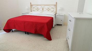 A bedroom with a bed, nightstands, a dresser, and a mirror.