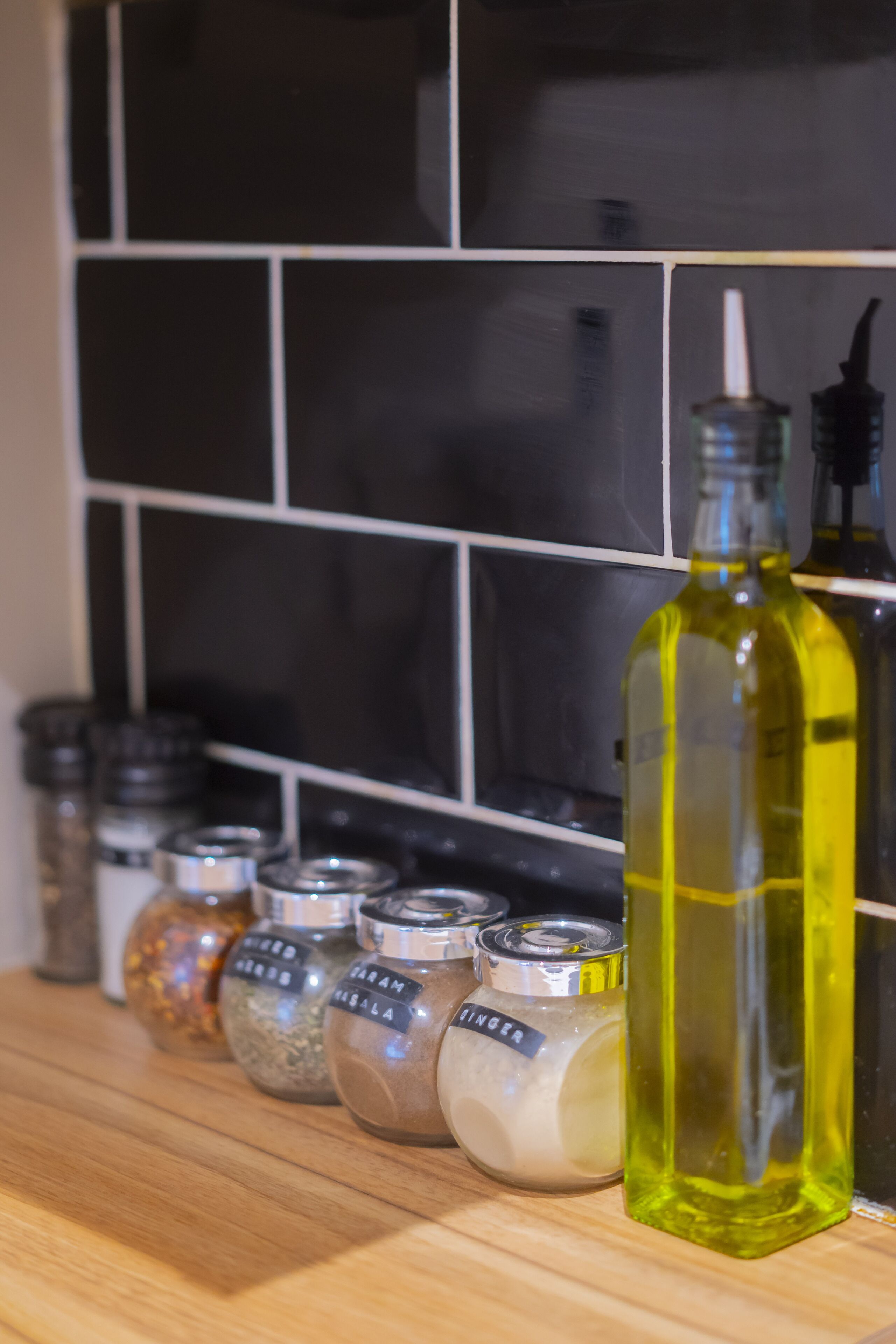 A kitchen counter with various spice jars and a bottle of oil.