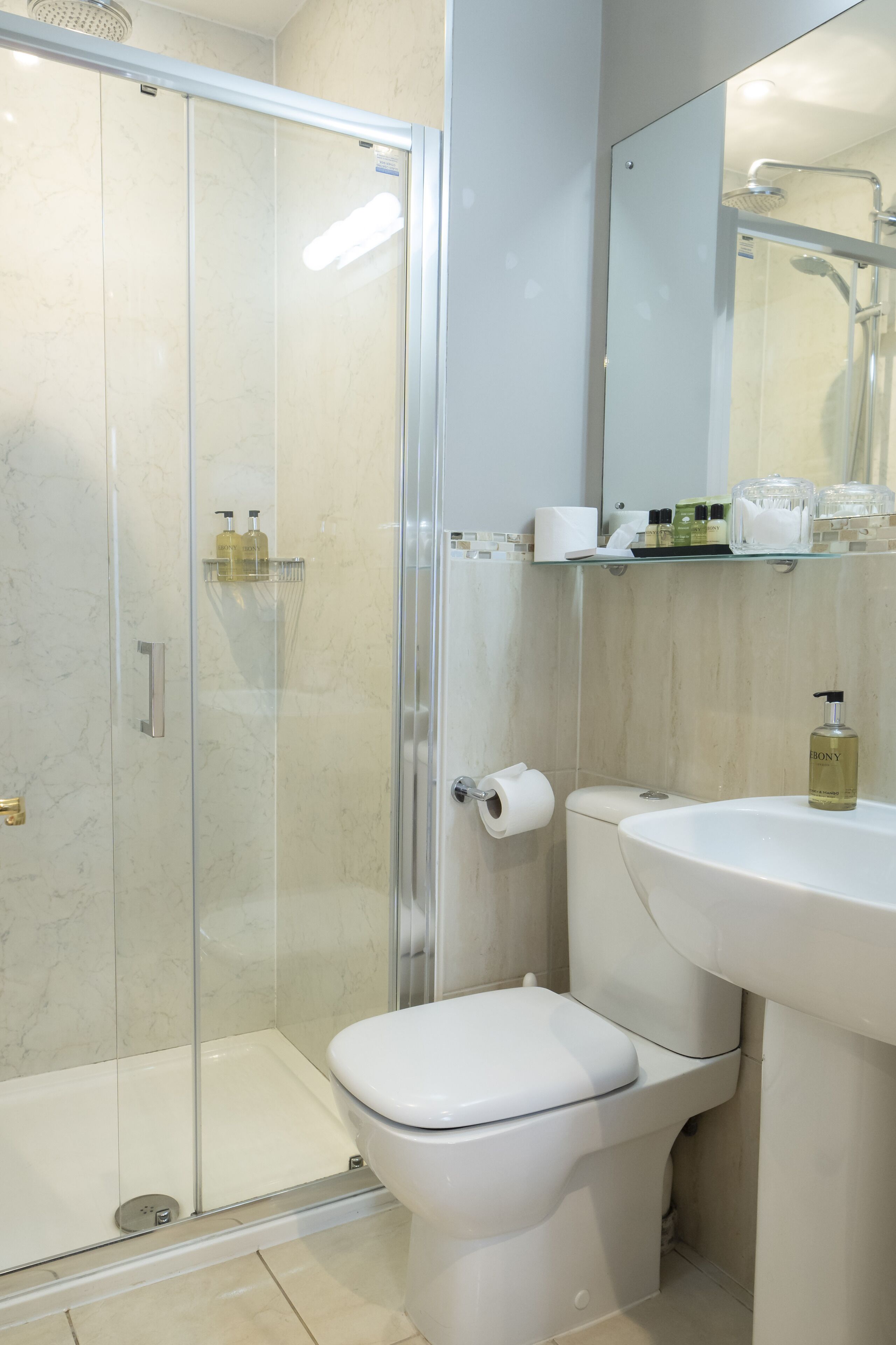 A bathroom with a glass-enclosed shower, a toilet, and a sink.