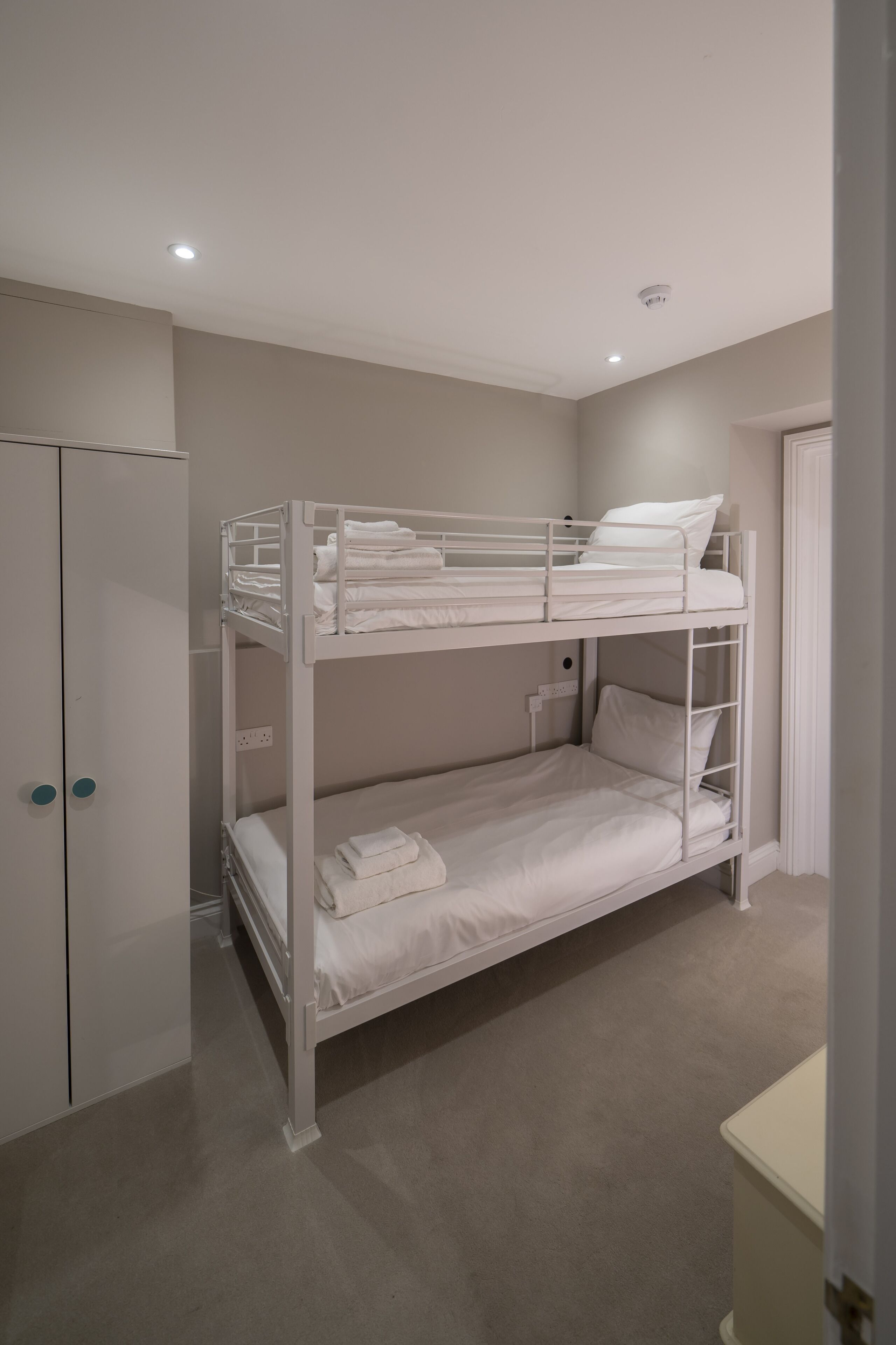 A bunk bed room with a wardrobe and a door.