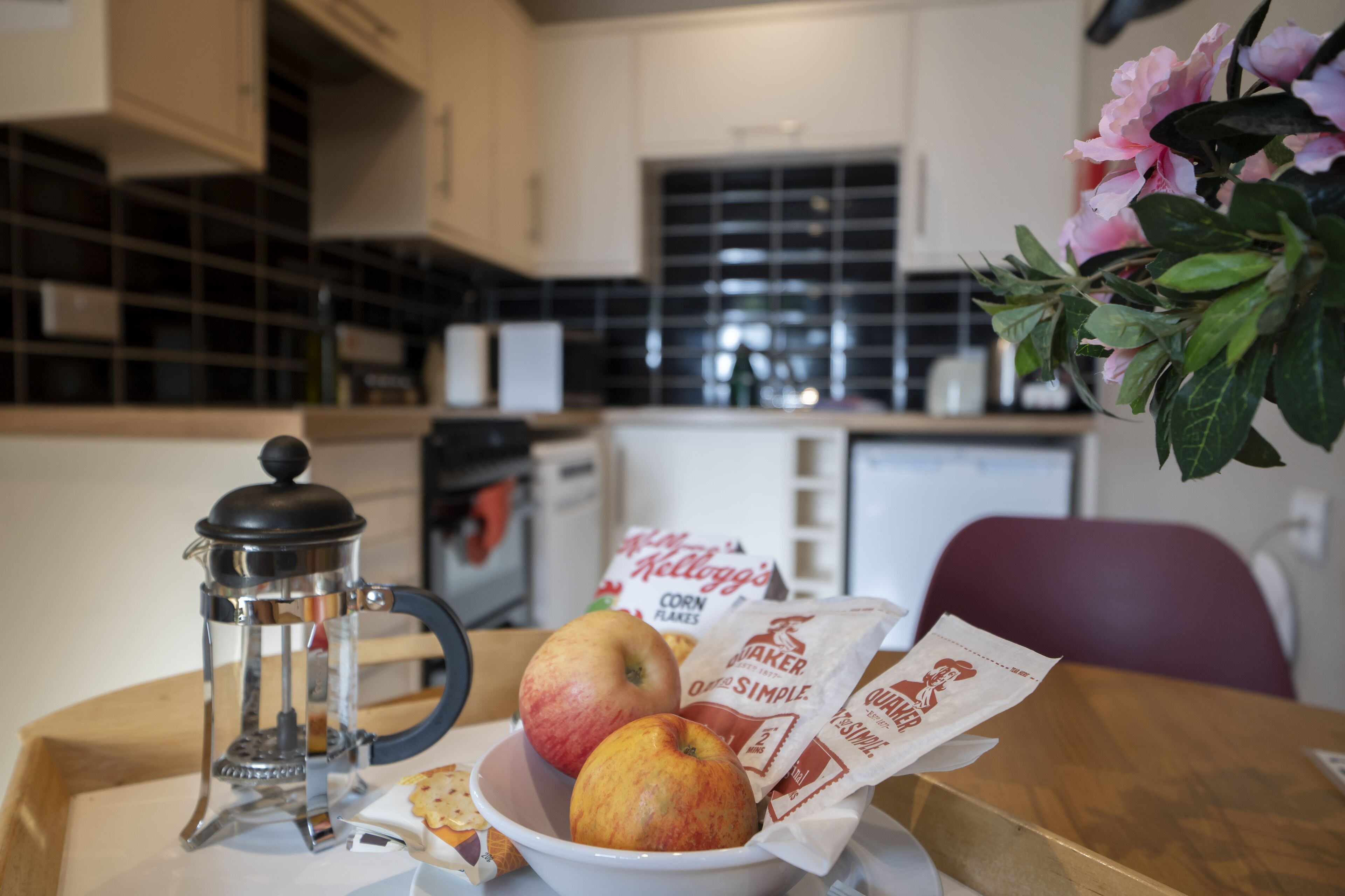 A kitchen with a coffee maker, a bowl of fruit, and coffee bags on the counter.