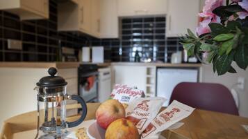 A kitchen with a coffee maker, a bowl of fruit, and coffee bags on the counter.