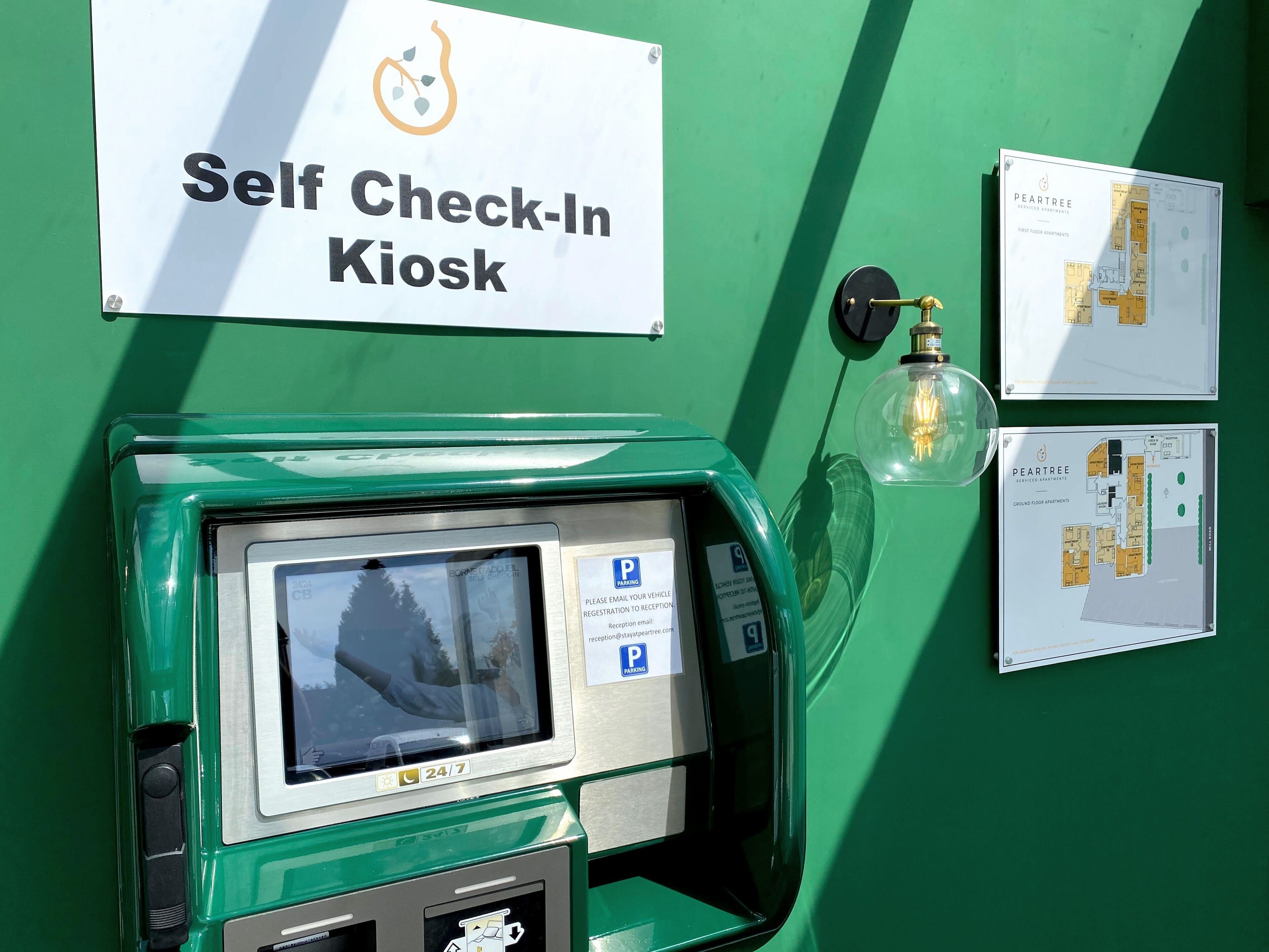 Un kiosque d’enregistrement automatisé doté d’un écran numérique, d’un panneau indiquant l’emplacement du parking et d’un plan des lieux.