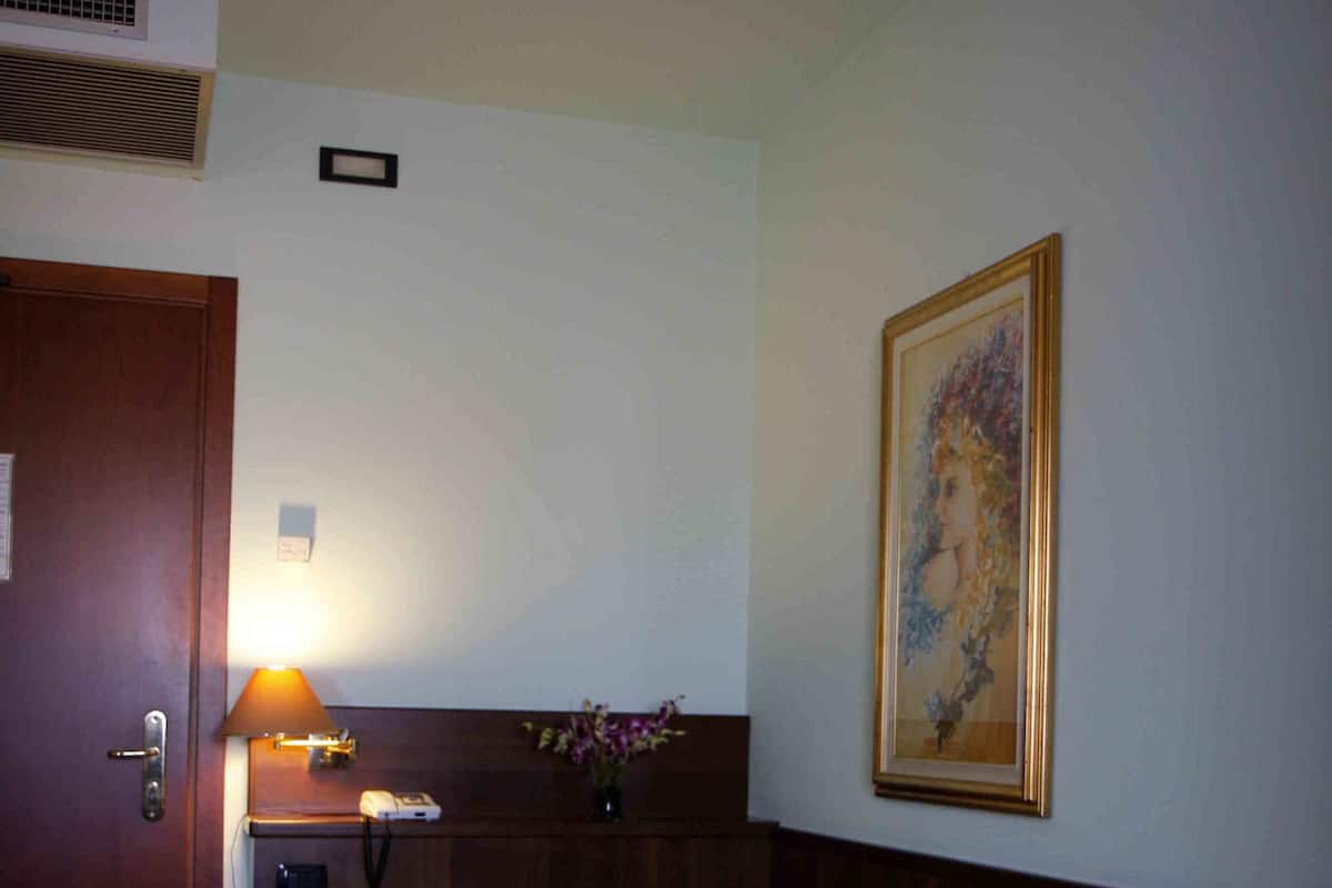 Ein Hotelzimmer mit Bett, Nachttisch, Lampe und einem gerahmten Bild an der Wand.