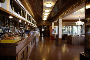 Eine Bar mit einer langen Theke, Regalen voller Flaschen und einer Vitrine mit Gebäck.