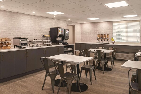 A modern restaurant with a brick wall, a coffee bar, and several tables and chairs.