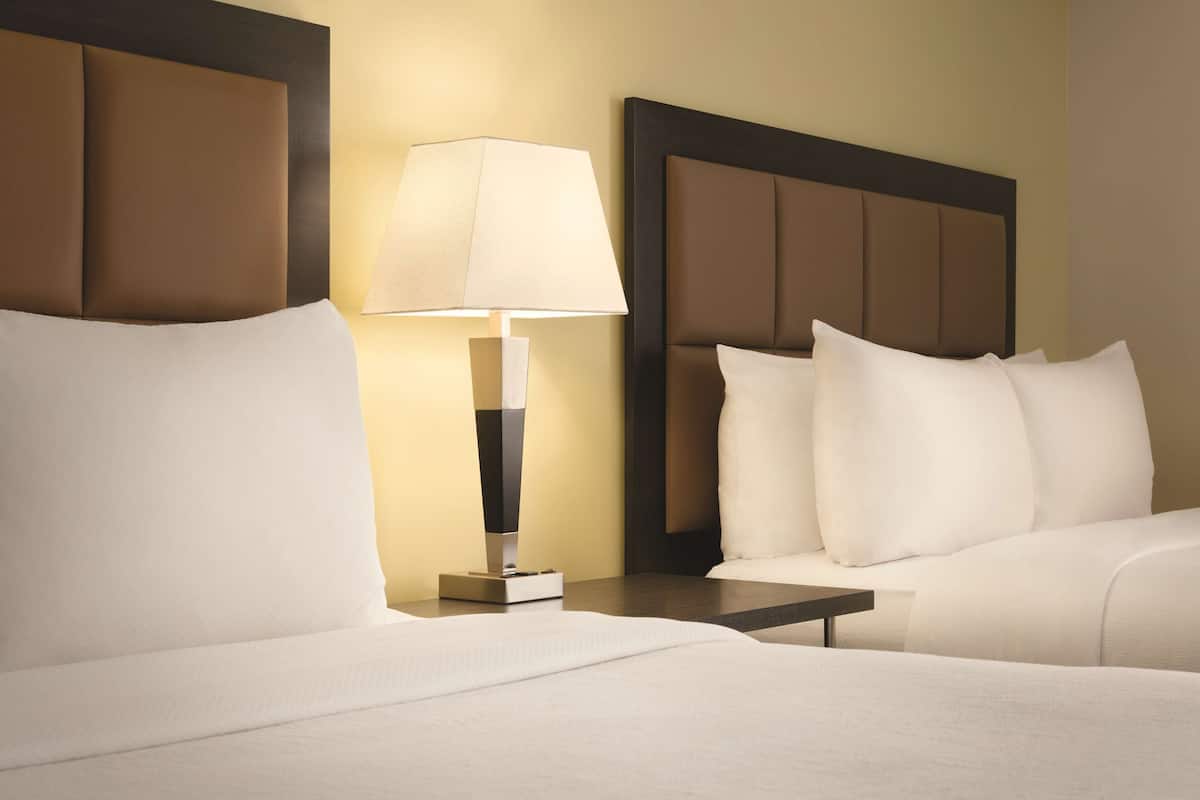 A hotel room with a bed, a nightstand, a lamp, and a headboard.