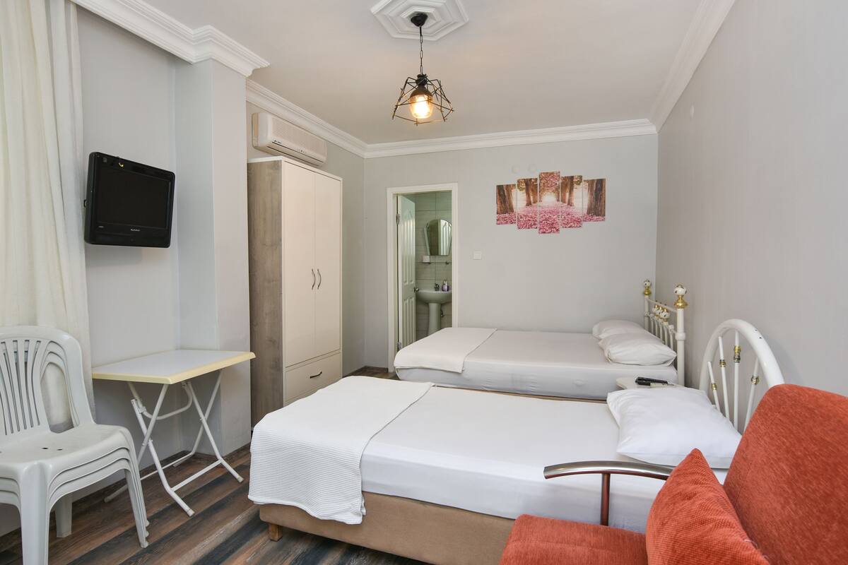 A bedroom with two beds, a desk, a chair, and a TV.