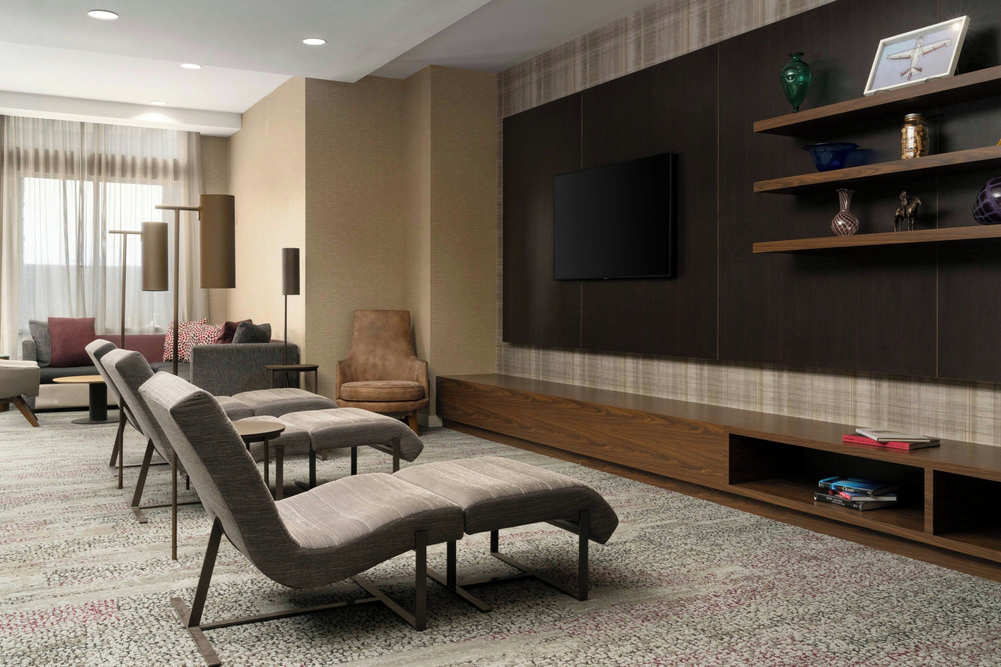 A modern living room with a flat-screen TV mounted on a dark wall, a sofa, a chair, and a coffee table.