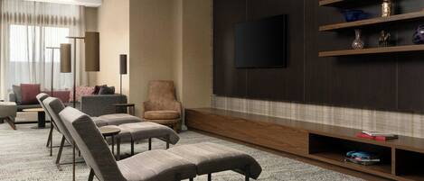A modern living room with a flat-screen TV mounted on a dark wall, a sofa, a chair, and a coffee table.