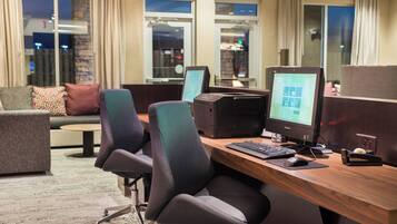 Een moderne kantoorruimte met een houten bureau, twee ergonomische stoelen, een computer en een printer.