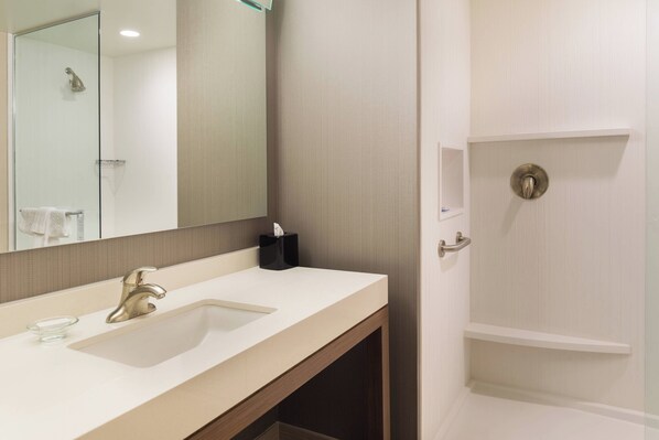 Un baño con lavamanos, espejo y ducha.