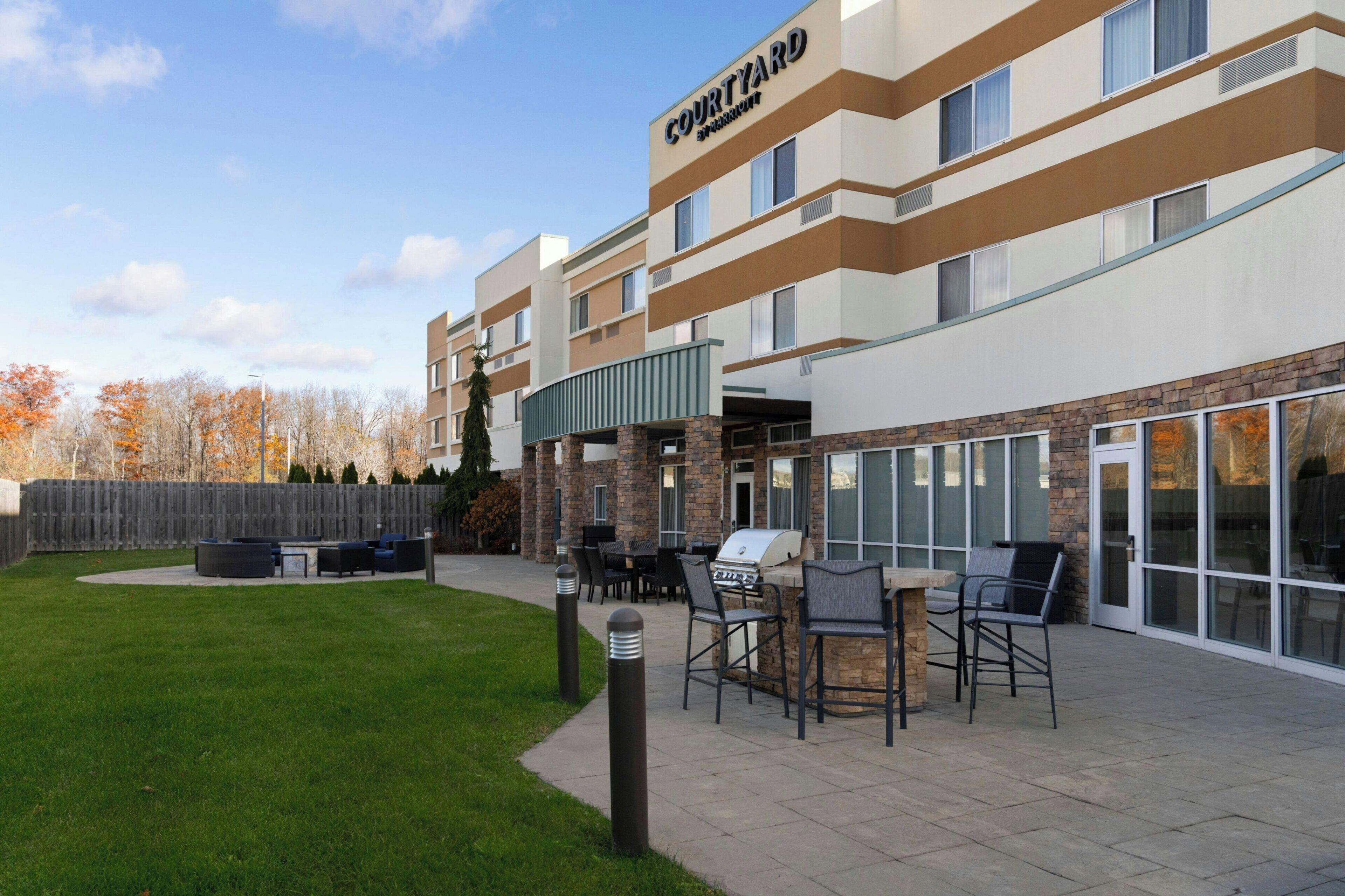 A Courtyard by Marriott hotel with outdoor seating and a barbecue area.