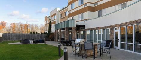 A Courtyard by Marriott hotel with outdoor seating and a barbecue area.