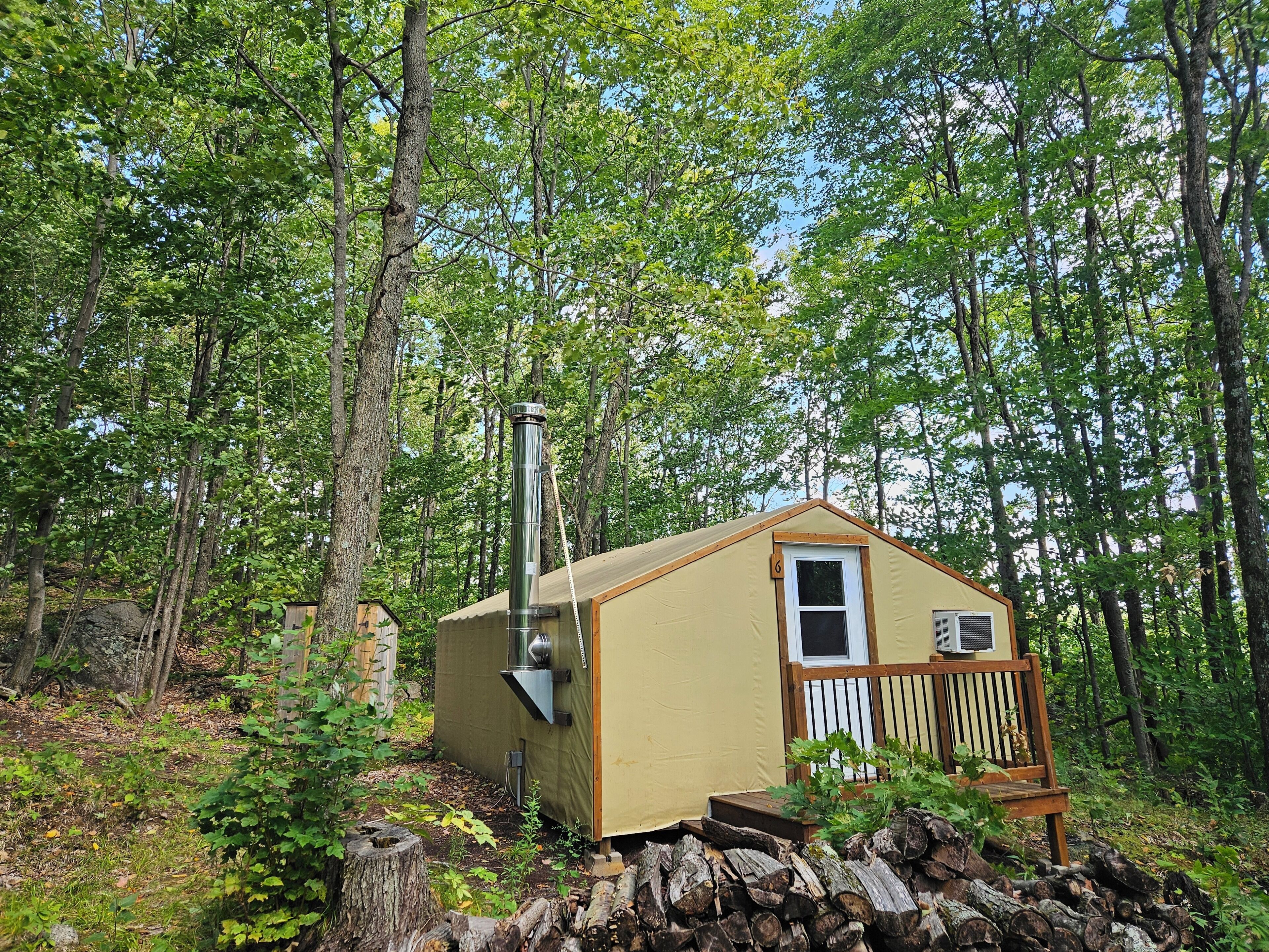 A small, single-story cabin with a chimney, surrounded by a forest.