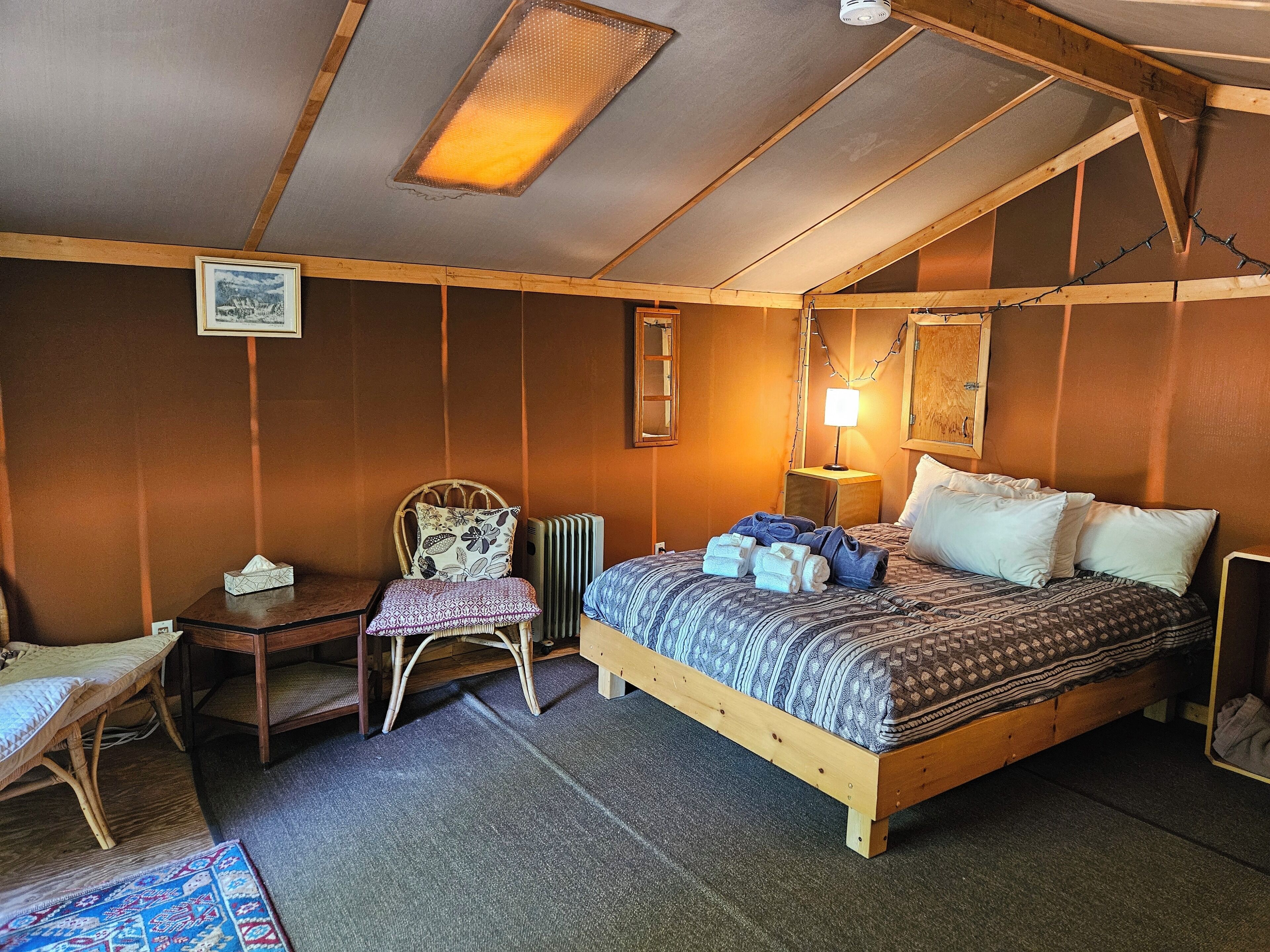 Een gezellige kamer met een houten bed, een stoel, een klein tafeltje en een radiator.