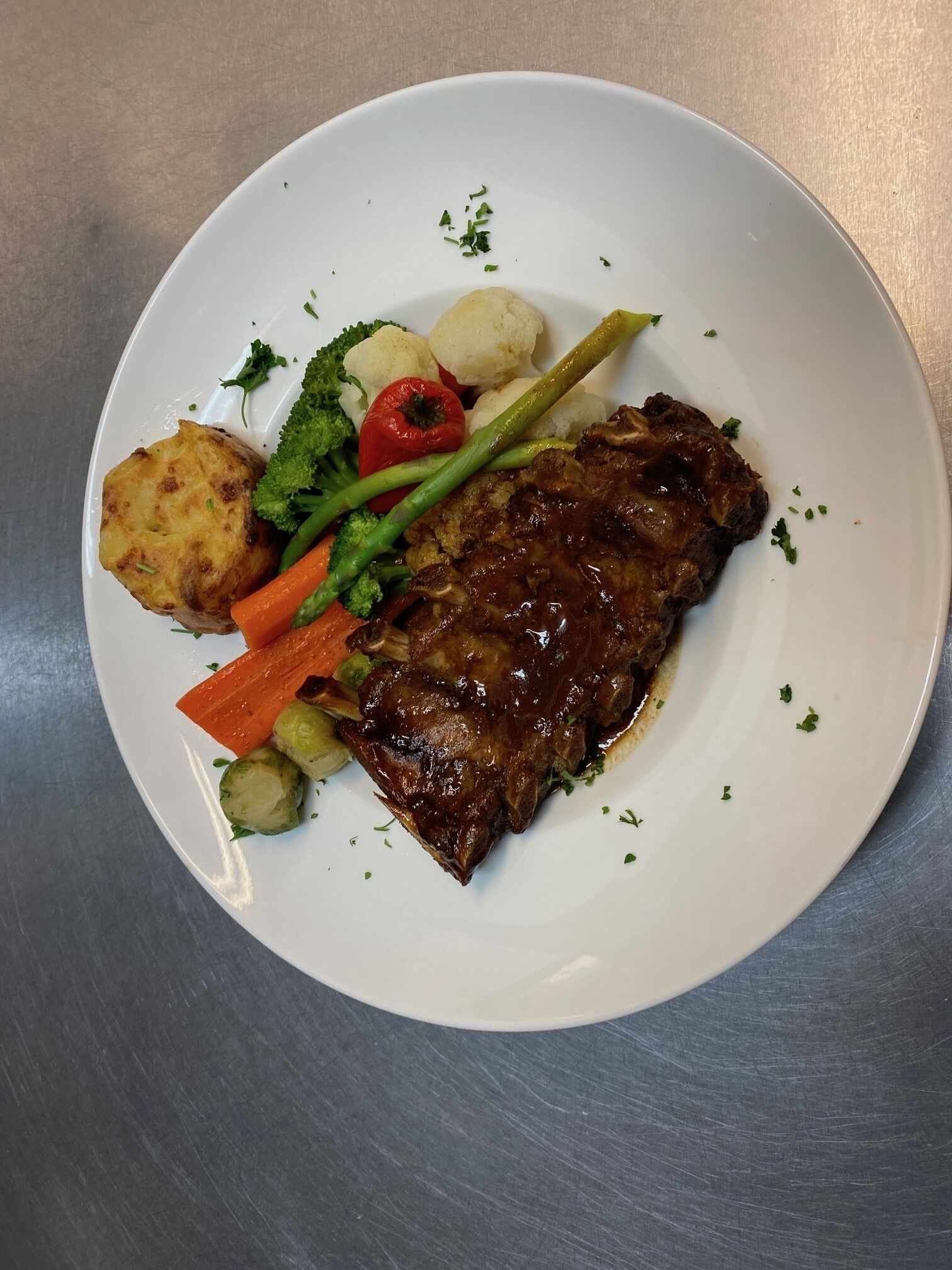 A plate with a steak, potatoes, carrots, and broccoli.