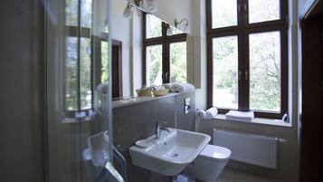 Une salle de bain avec un lavabo, des toilettes et de grandes fenêtres.