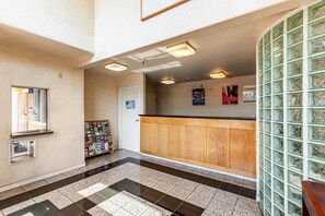 A reception area with a wooden counter, a glass display case, and a tiled floor. - Motel 6 Stockton Ca East (Stockton)