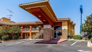 A hotel with a red facade, a covered entrance, and a parking lot. - Motel 6 Stockton Ca East (Stockton)