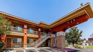 A building with a red facade, a covered entrance, and a parking lot. - Motel 6 Stockton Ca East (Stockton)