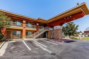 A two-story building with a red facade, a covered parking area, and a staircase leading to the entrance.