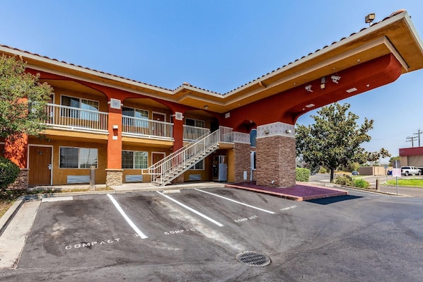 A two-story building with a red facade, a covered parking area, and a staircase leading to the entrance. - Motel 6 Stockton Ca East (Stockton)