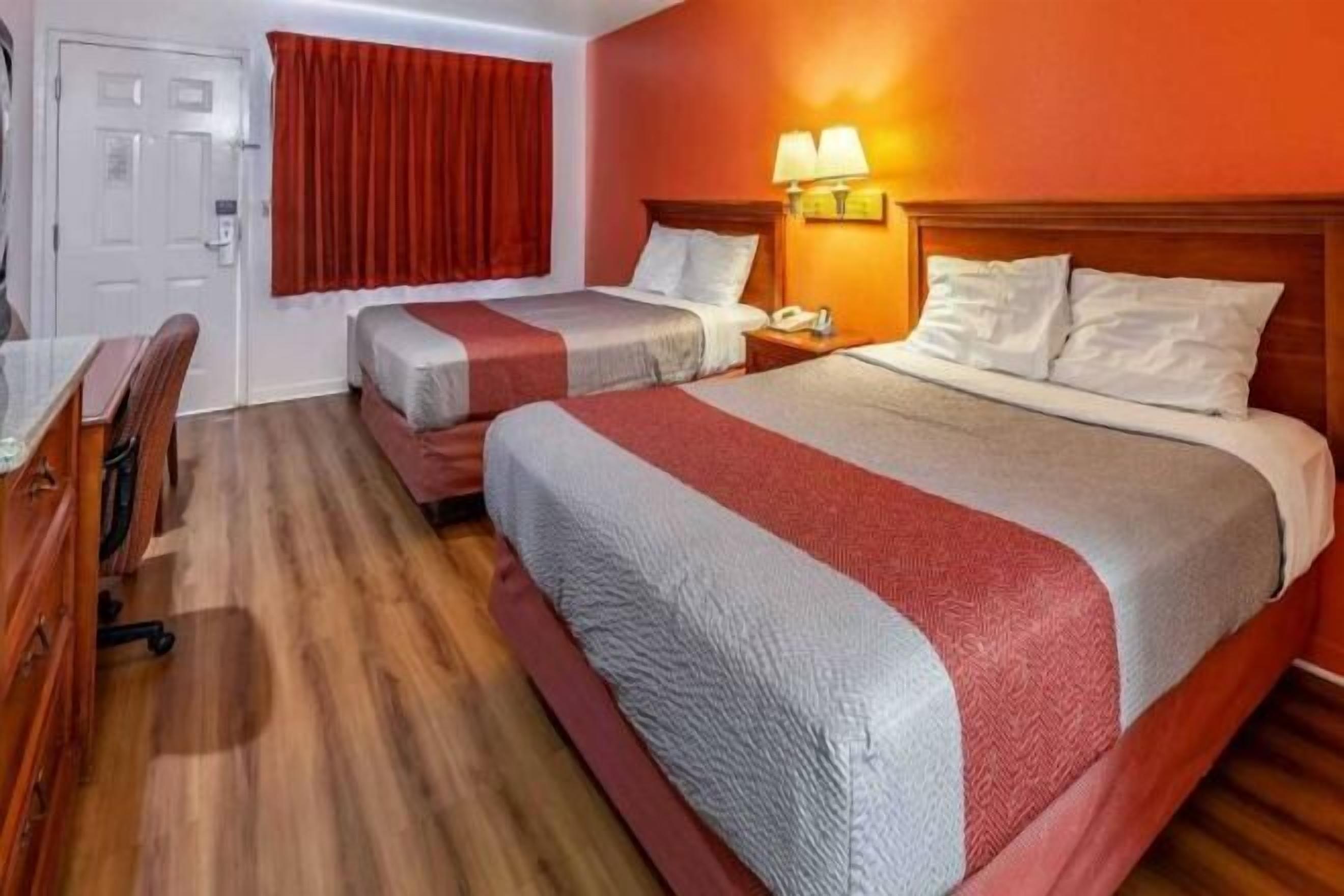 A hotel room with two beds, a desk, and a chair.